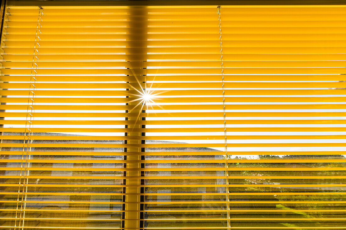 Sonne, die durch gelbe Fensterläden scheint