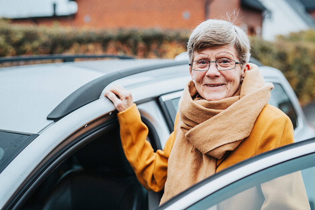 Ältere Frau neben Auto