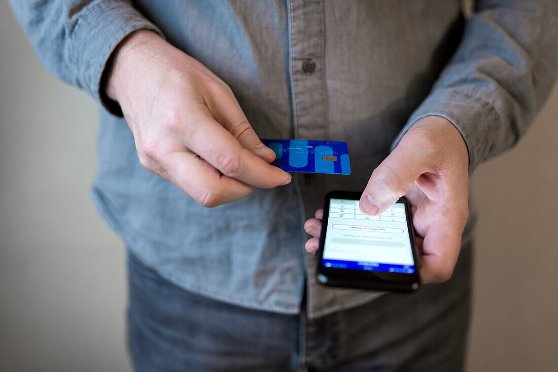 Hands holding credit card and cell phone