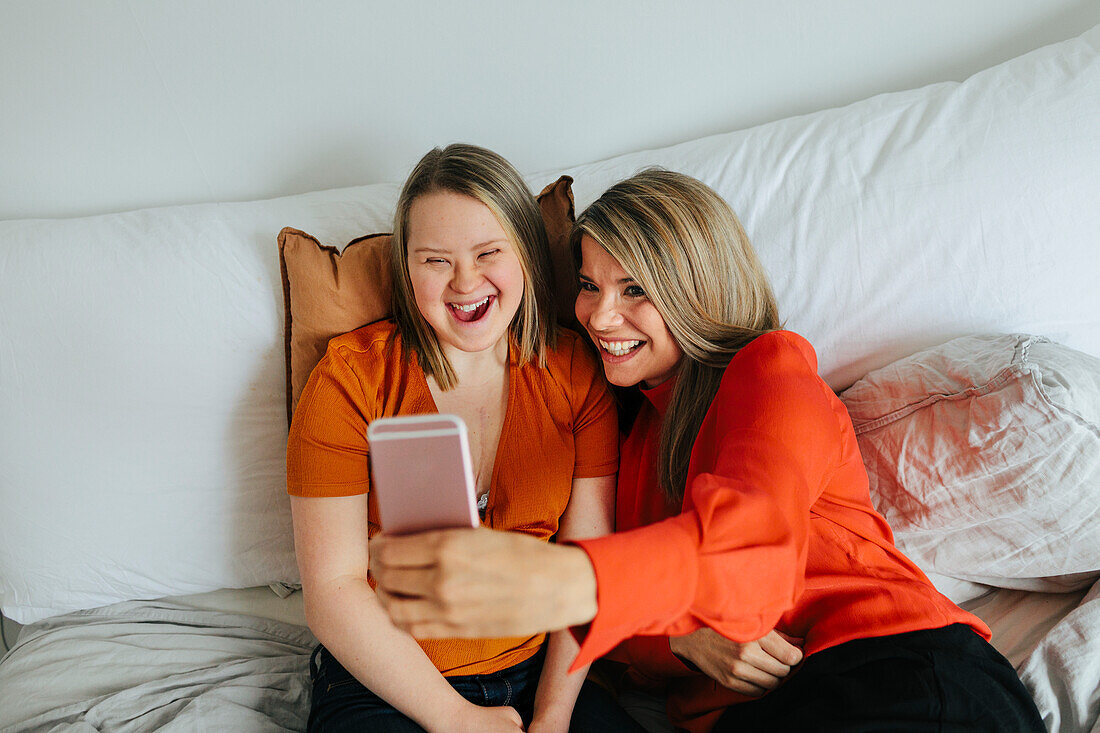 Sisters on bed taking selfie