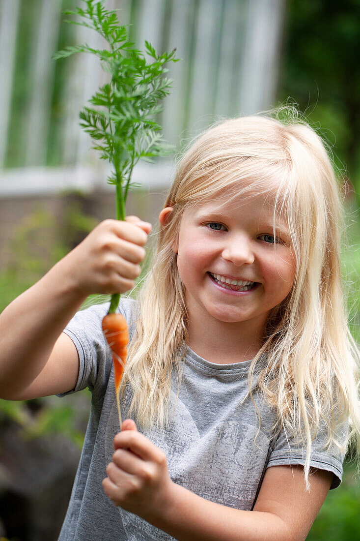 Smiling girl holding carrot