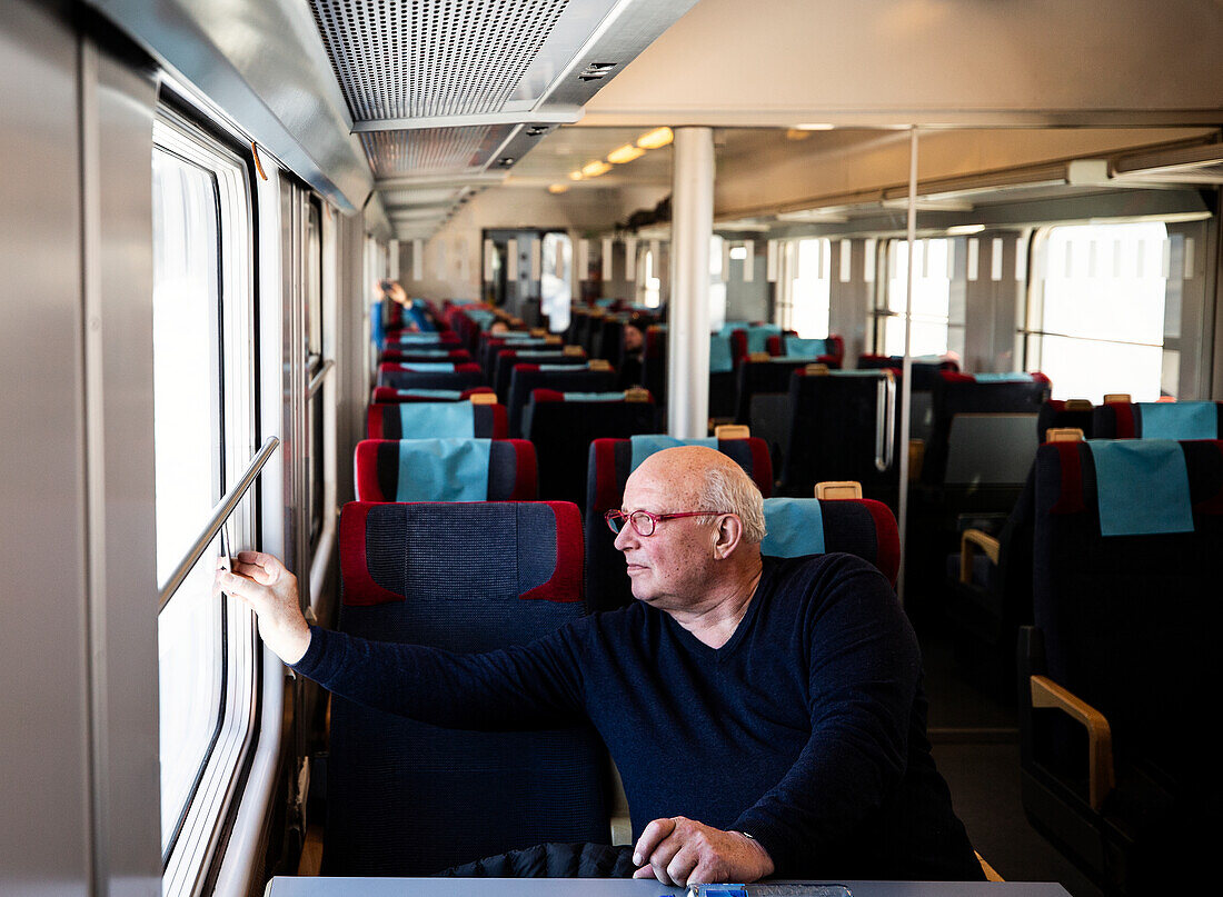 Älterer Mann schaut durch ein Zugfenster