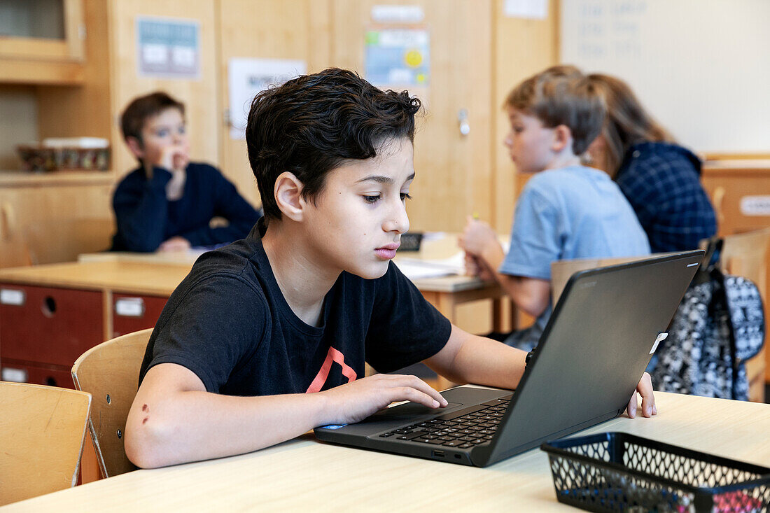 Junge benutzt Laptop in der Schule