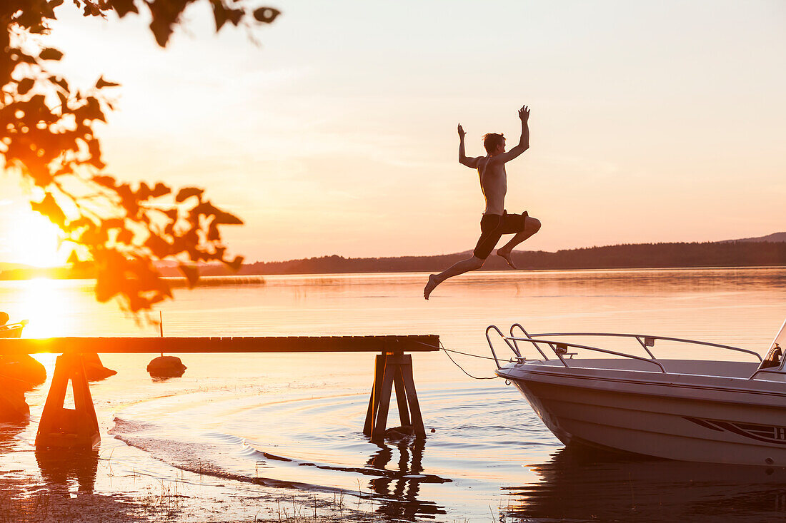Mann springt bei Sonnenuntergang ins Wasser