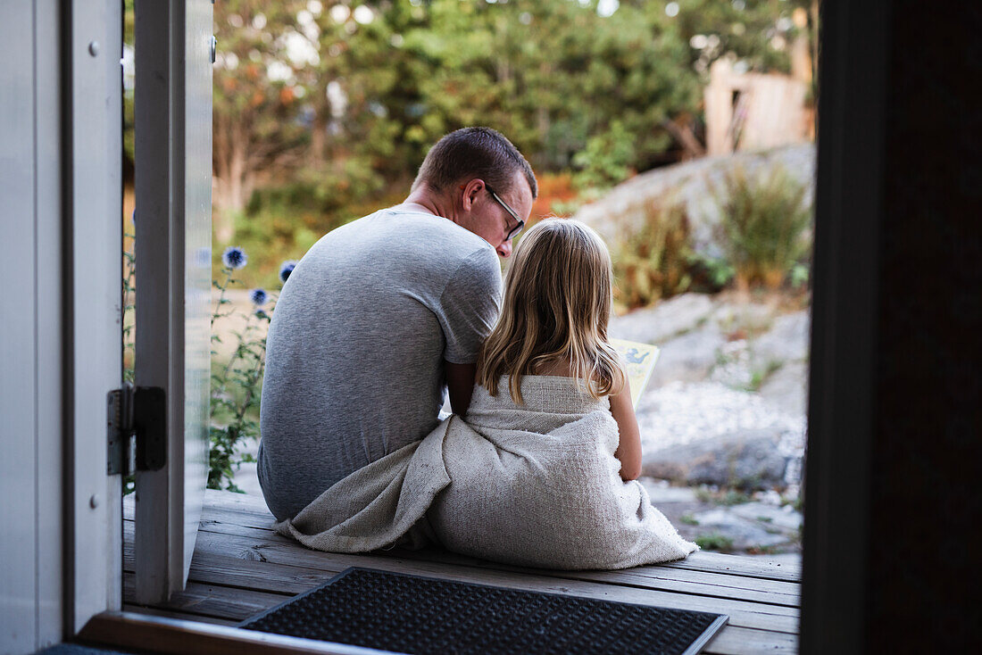 Father and daughter sitting at doorstep