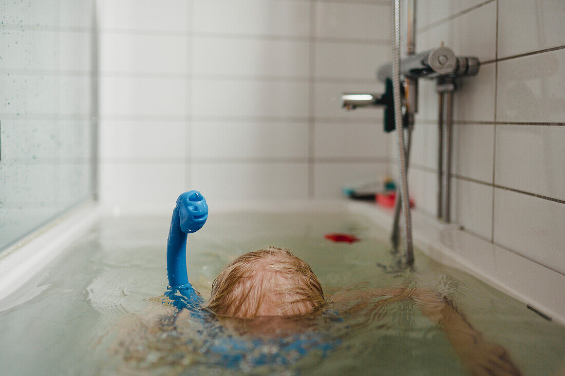 Child wearing snorkel in bathtub