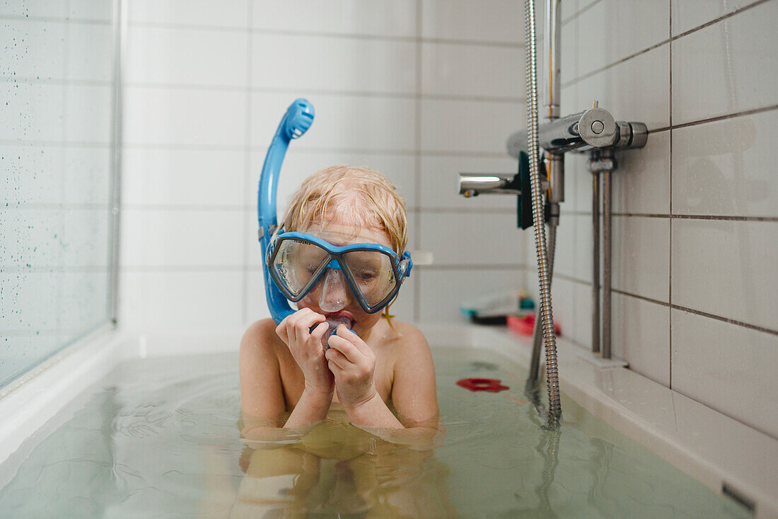 Boy wearing scuba mask in bathtub