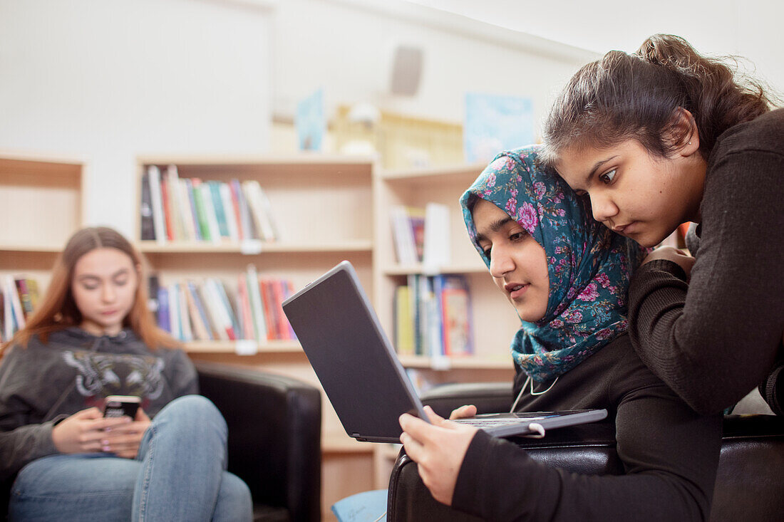 Mädchen im Teenageralter sitzen zusammen in der Bibliothek