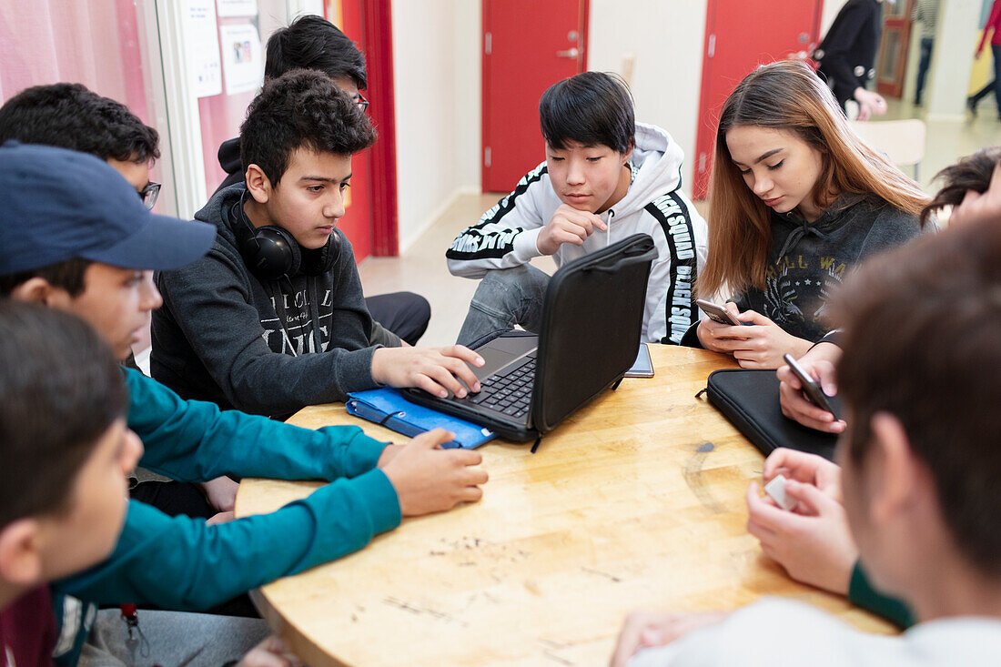 Teenager sitzen zusammen und benutzen einen Laptop