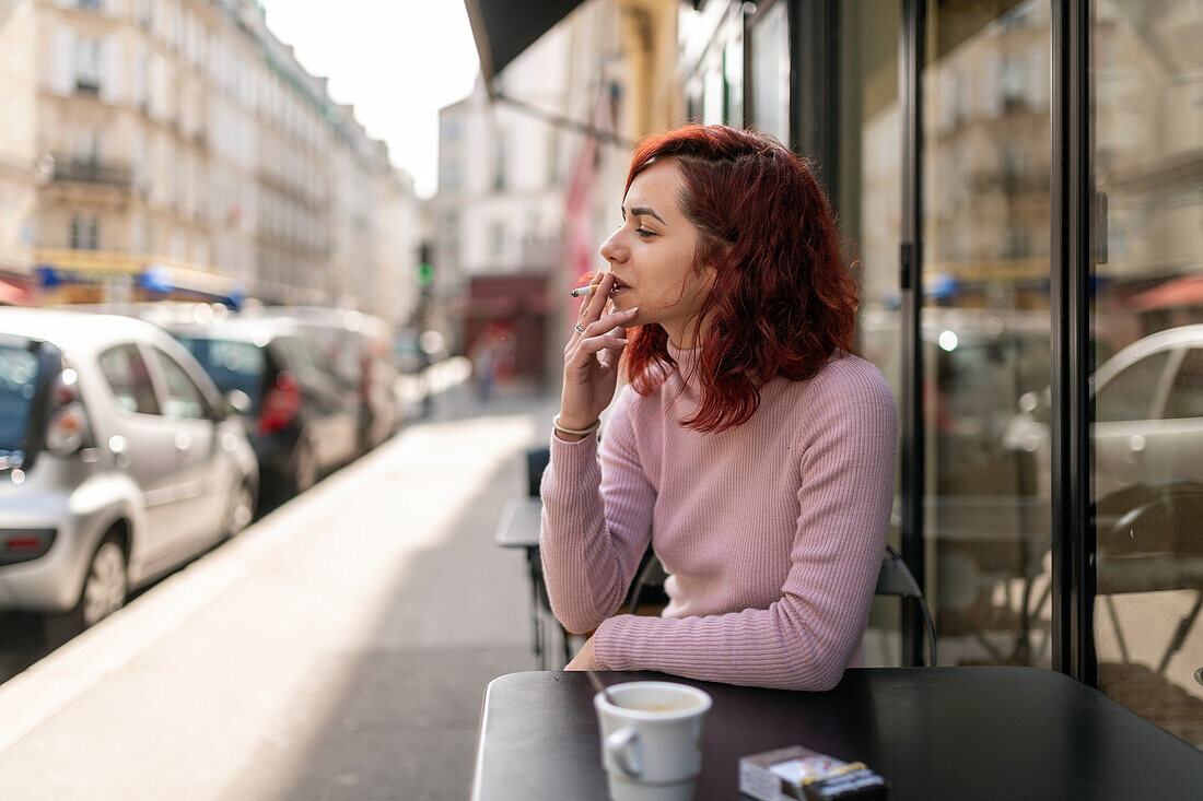 Frau raucht in einem Straßencafé
