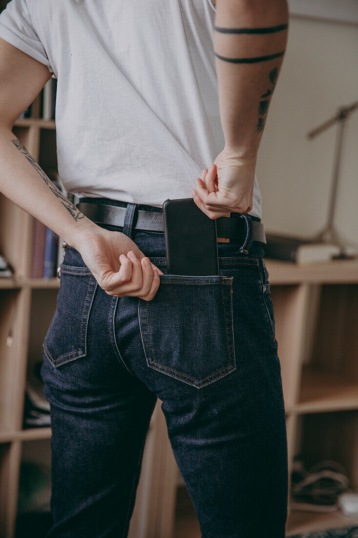 Woman placing cell phone in back pocket