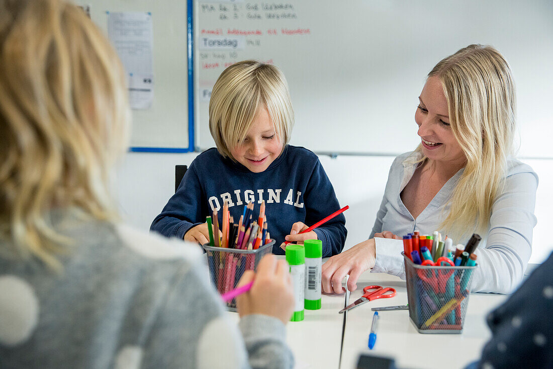 Lehrerin hilft einem Jungen im Klassenzimmer