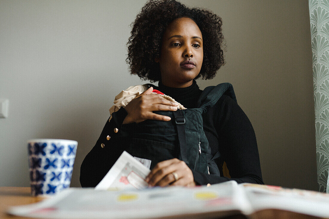 Woman with baby reading newspaper