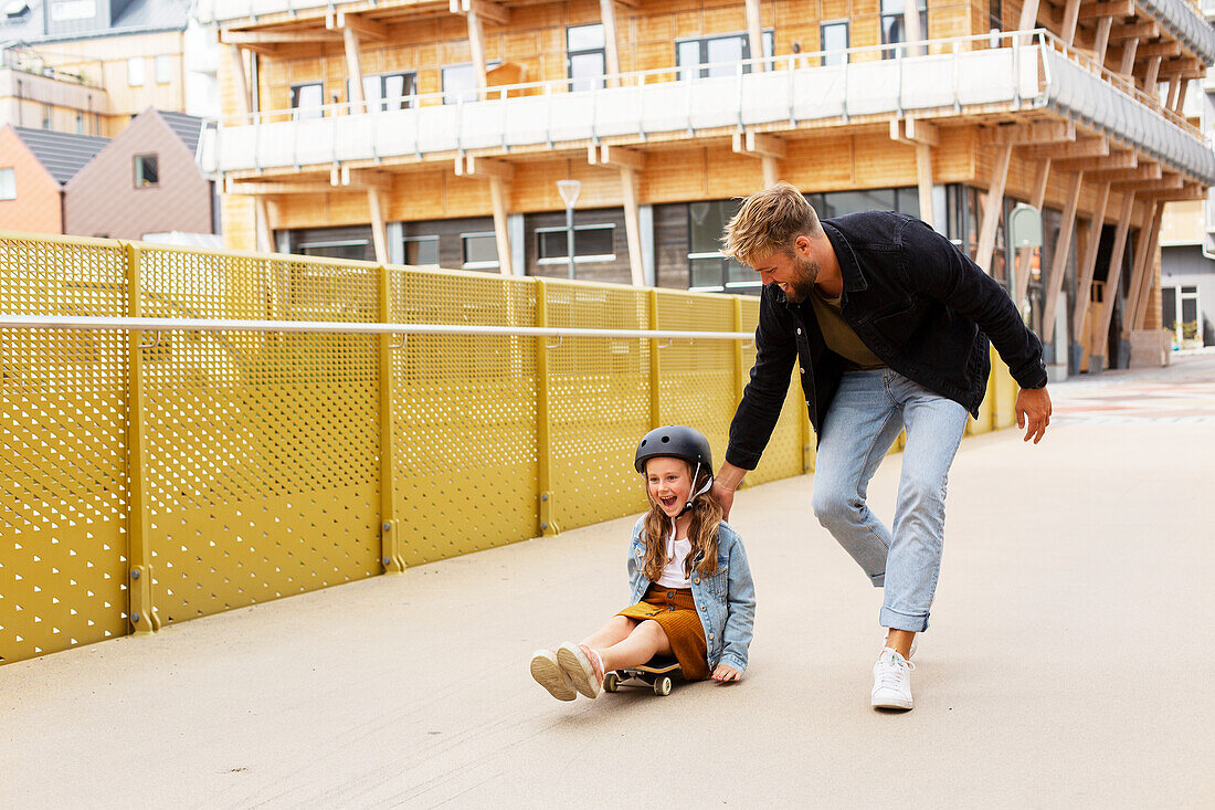 Mädchen auf Skateboard mit Vater