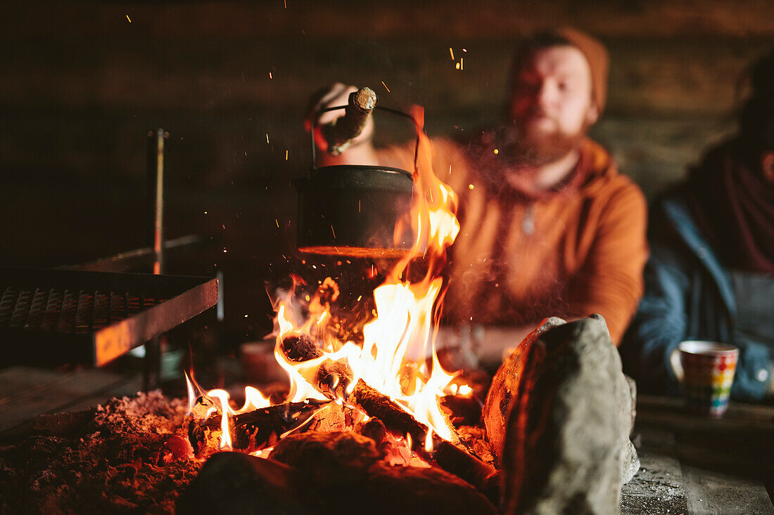 Mann setzt Kessel auf Lagerfeuer