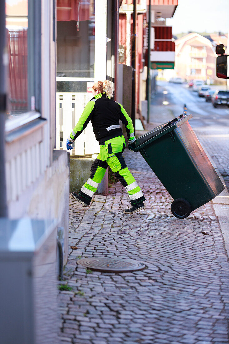Frau beim Ziehen der Mülltonne