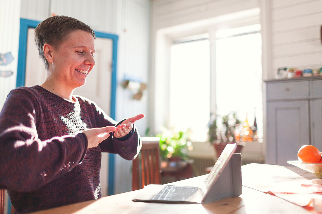 Frau unterhält sich in Gebärdensprache per Videoanruf am Computer
