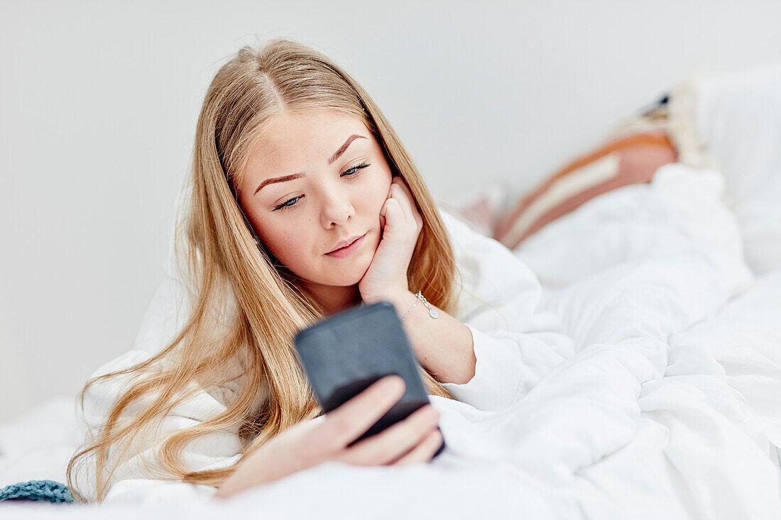 Woman in bed using cell phone