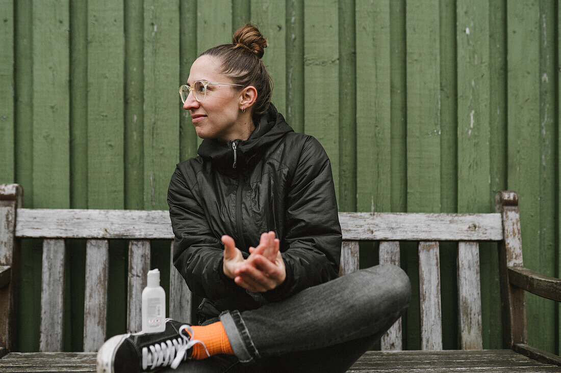 Woman on bench applying antibacterial gel on her hands