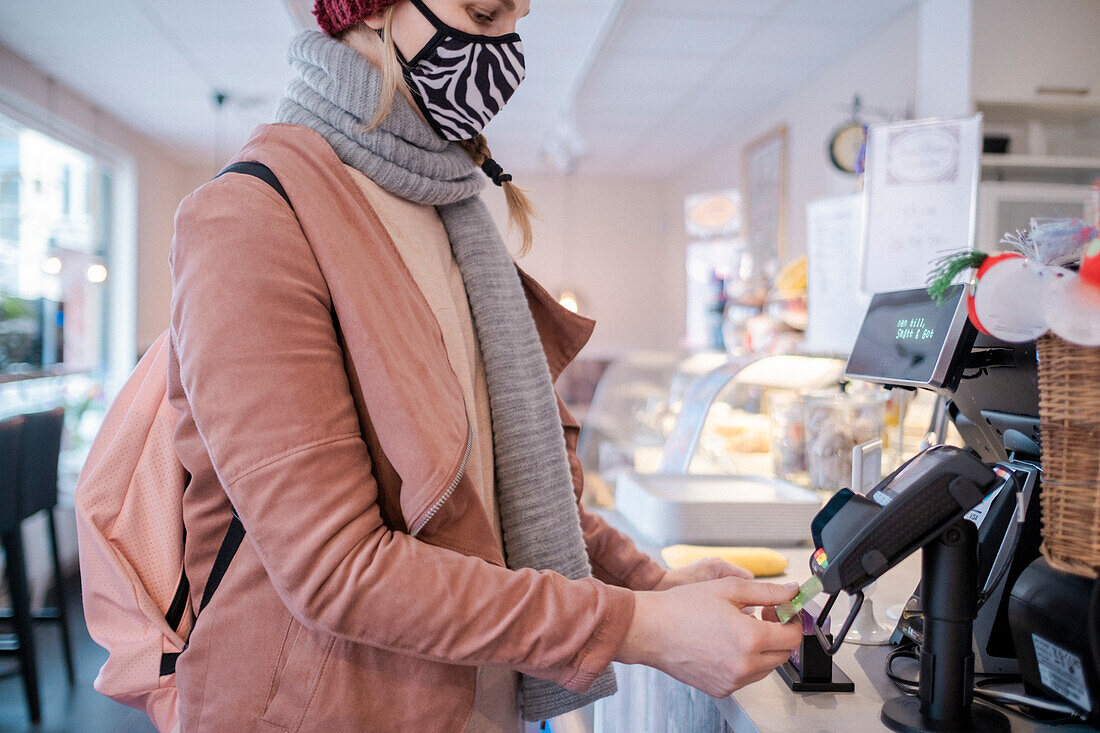 Frau mit Gesichtsmaske beim Bezahlen