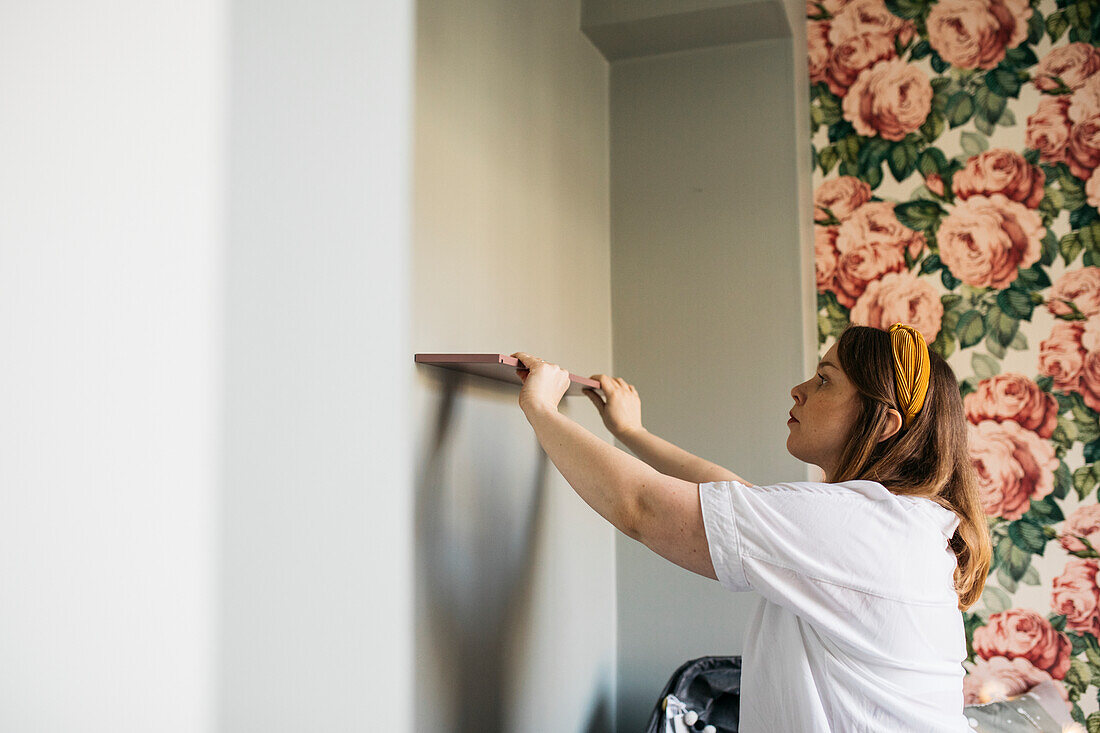 Woman putting shelf on wall