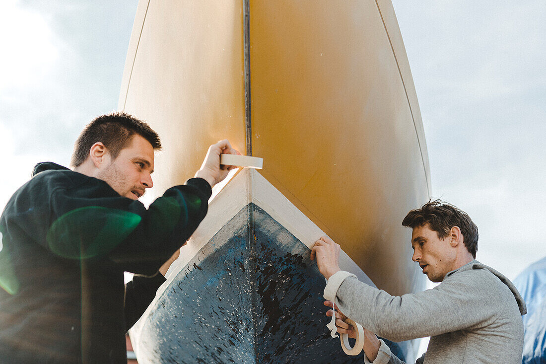 Männer kleben Abdeckband auf Boot