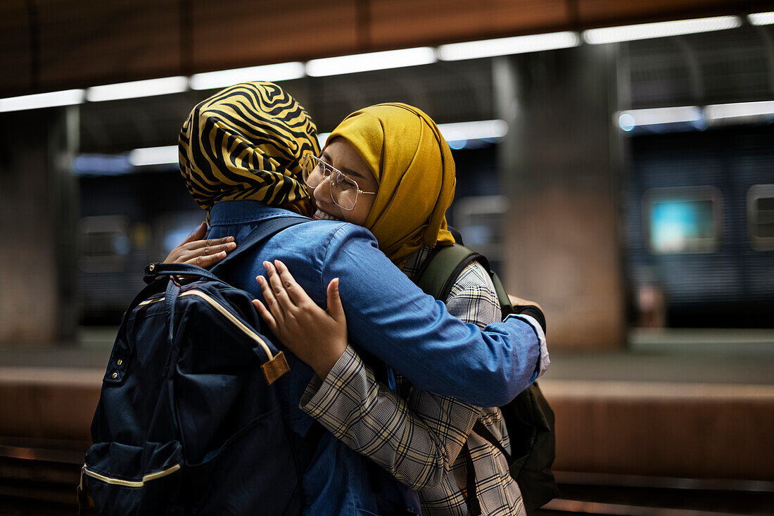 Freundinnen umarmen sich auf dem Bahnsteig