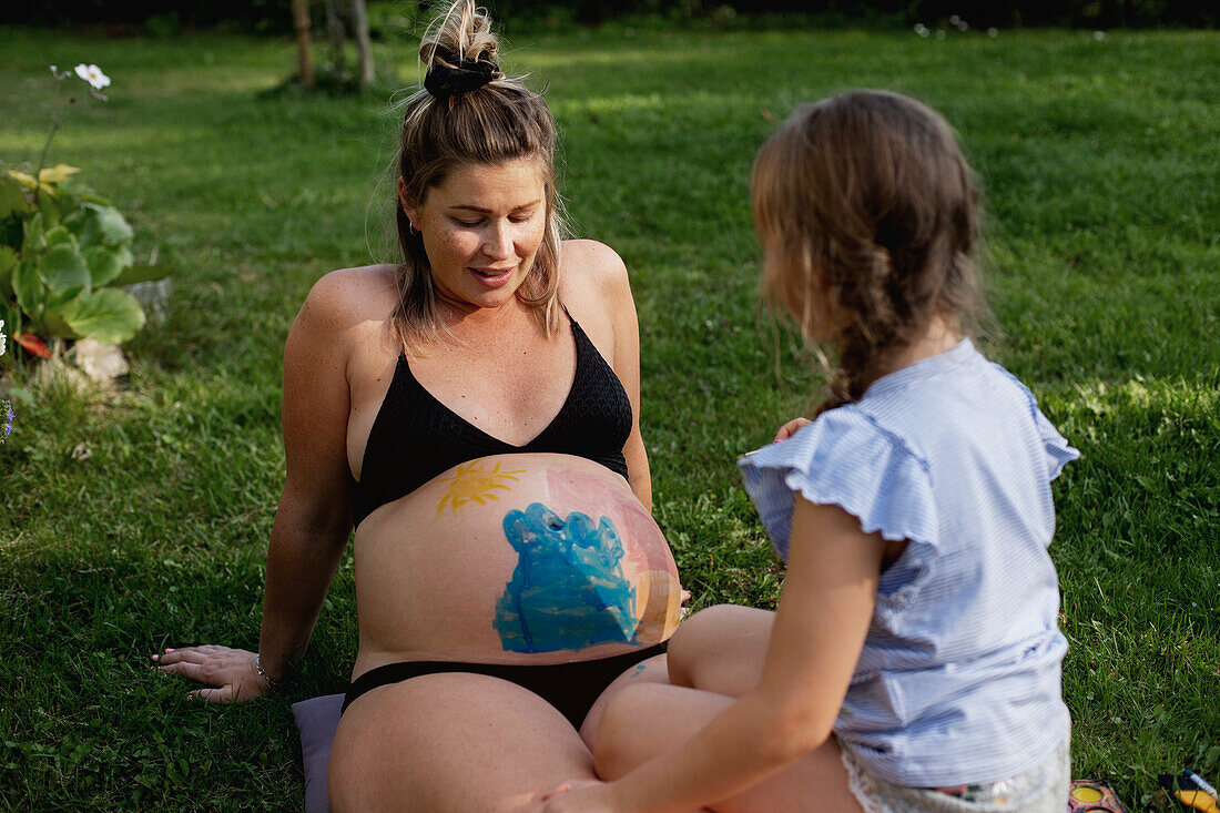 Mother with daughter sitting on lawn