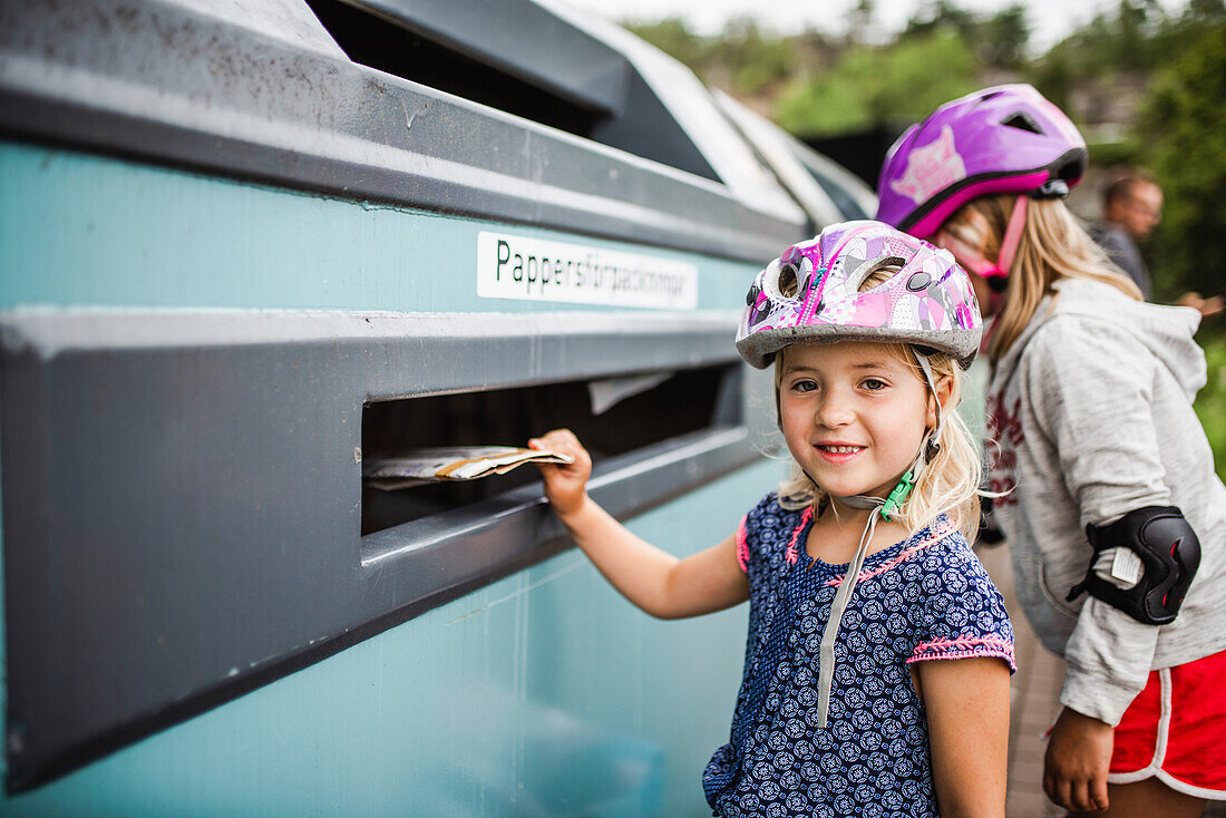 Mädchen wirft Müll in die Recycling-Tonne