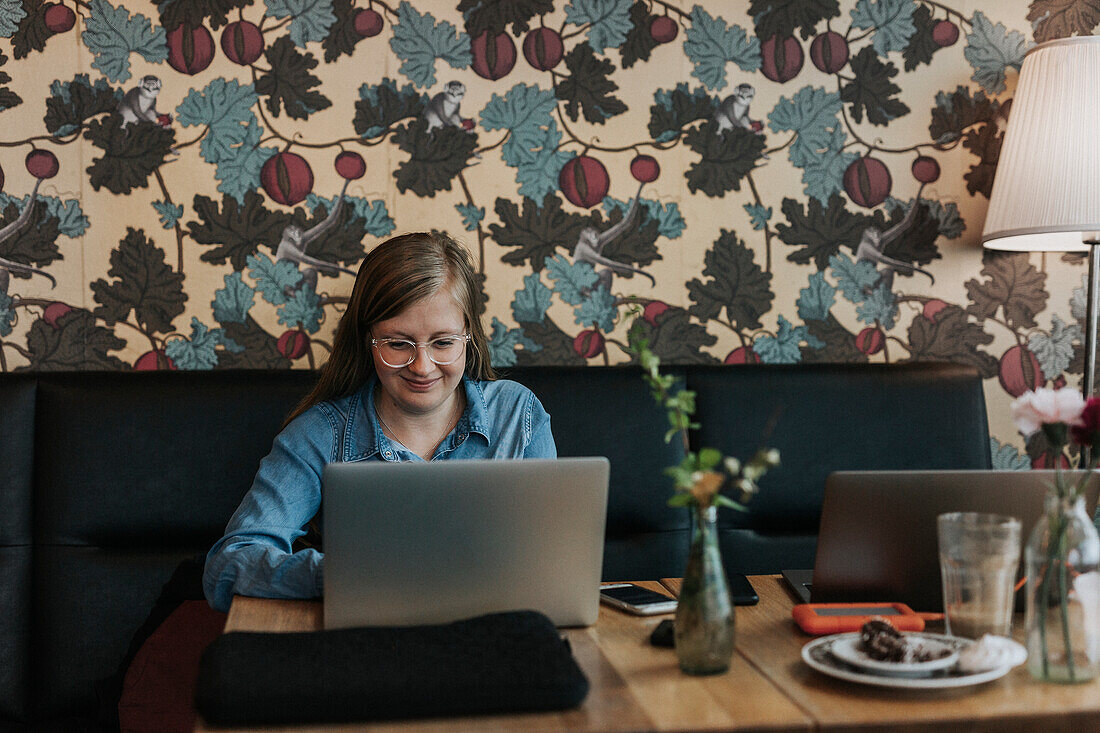 Lächelnde Frau mit Laptop im Cafe