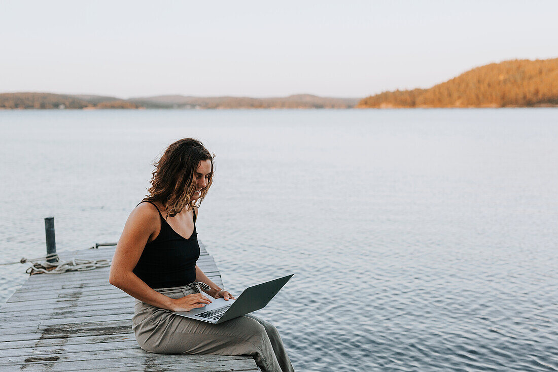 Woman on jetty using laptop