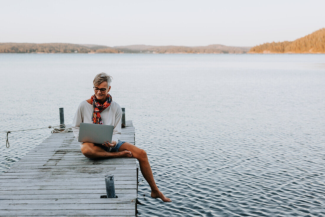 Woman on jetty using laptop