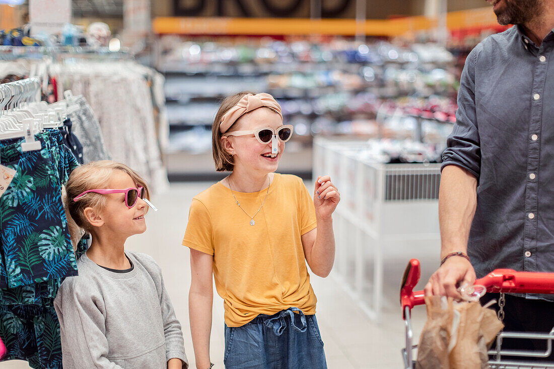 Lächelnde Mädchen probieren Sonnenbrillen in einem Geschäft