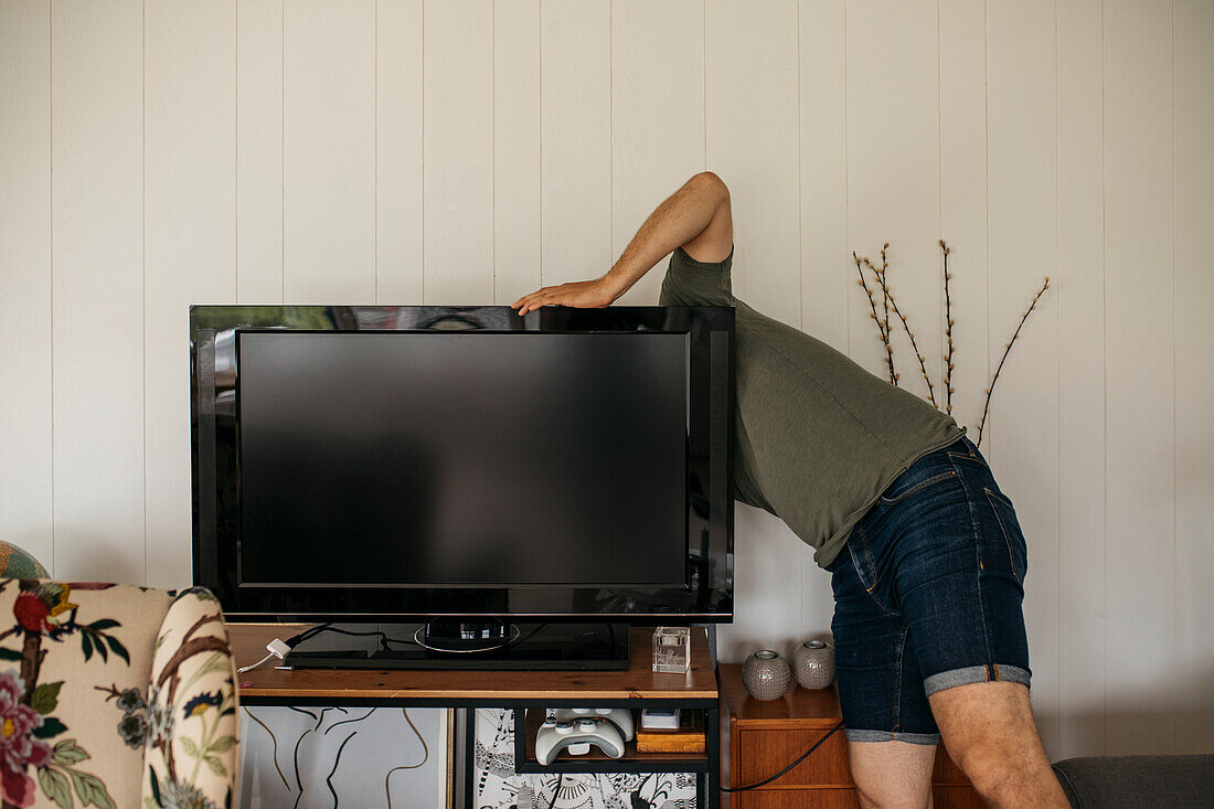 Man checking back of TV