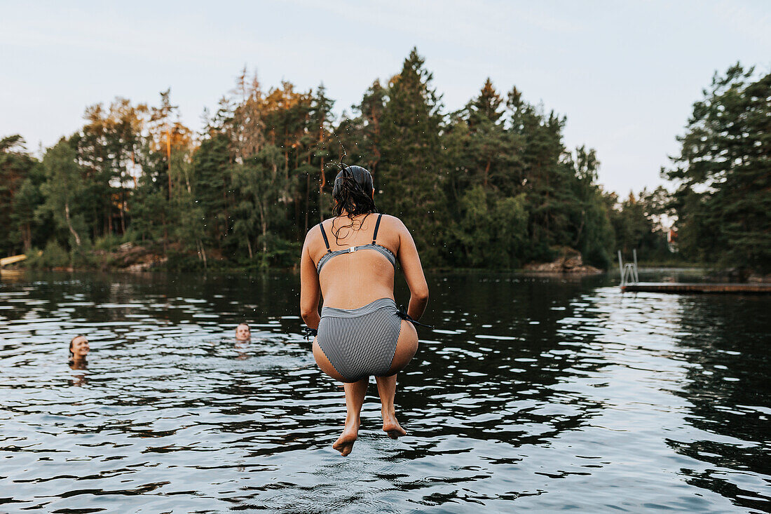 Rear view of woman jumping into water