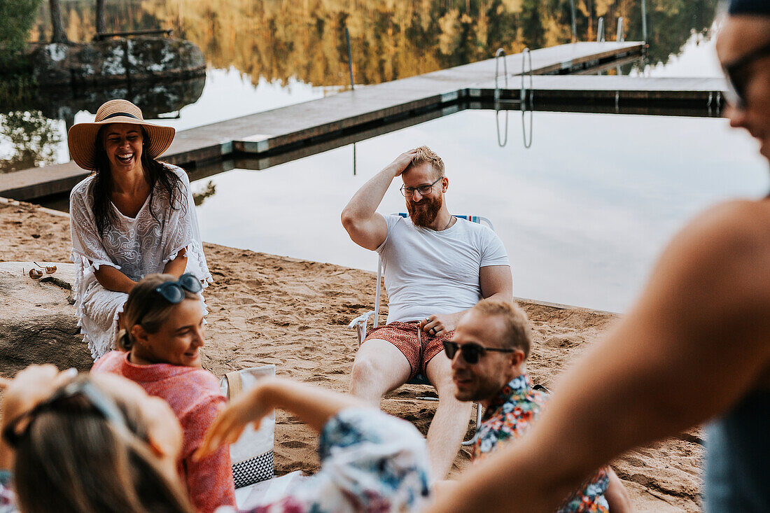 Glückliche Freunde sitzen am See