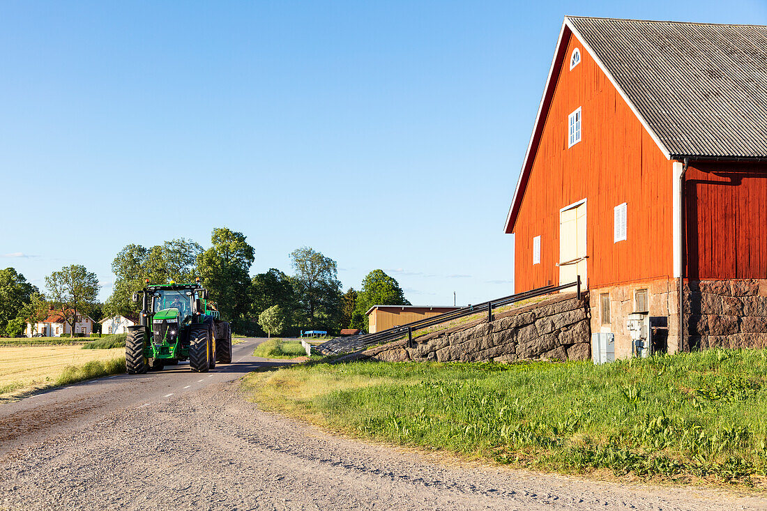 Tractor on dirt road near barn