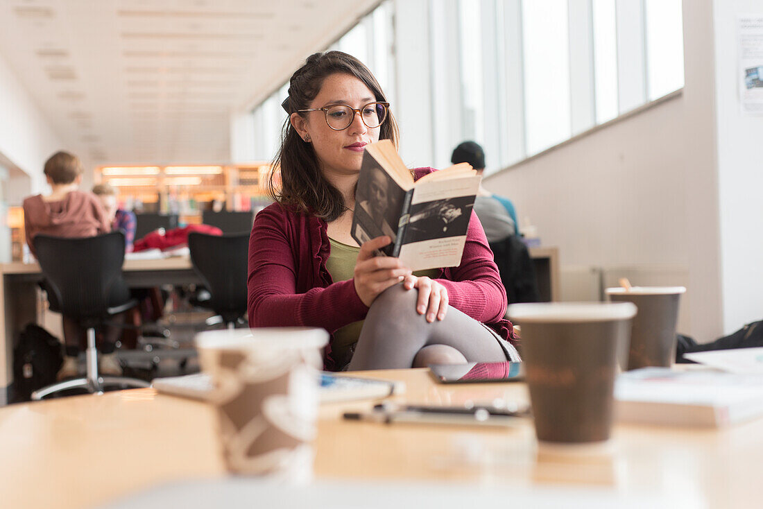 Frau liest Buch in der Bibliothek