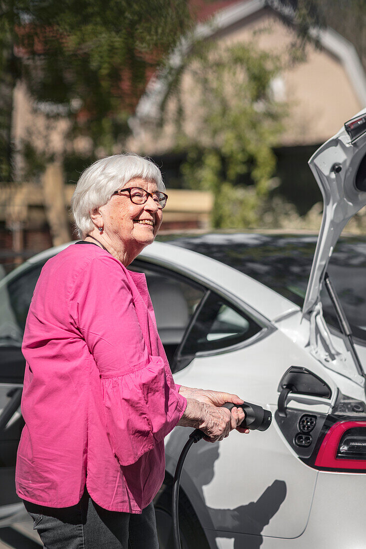 Smiling woman charging electric car