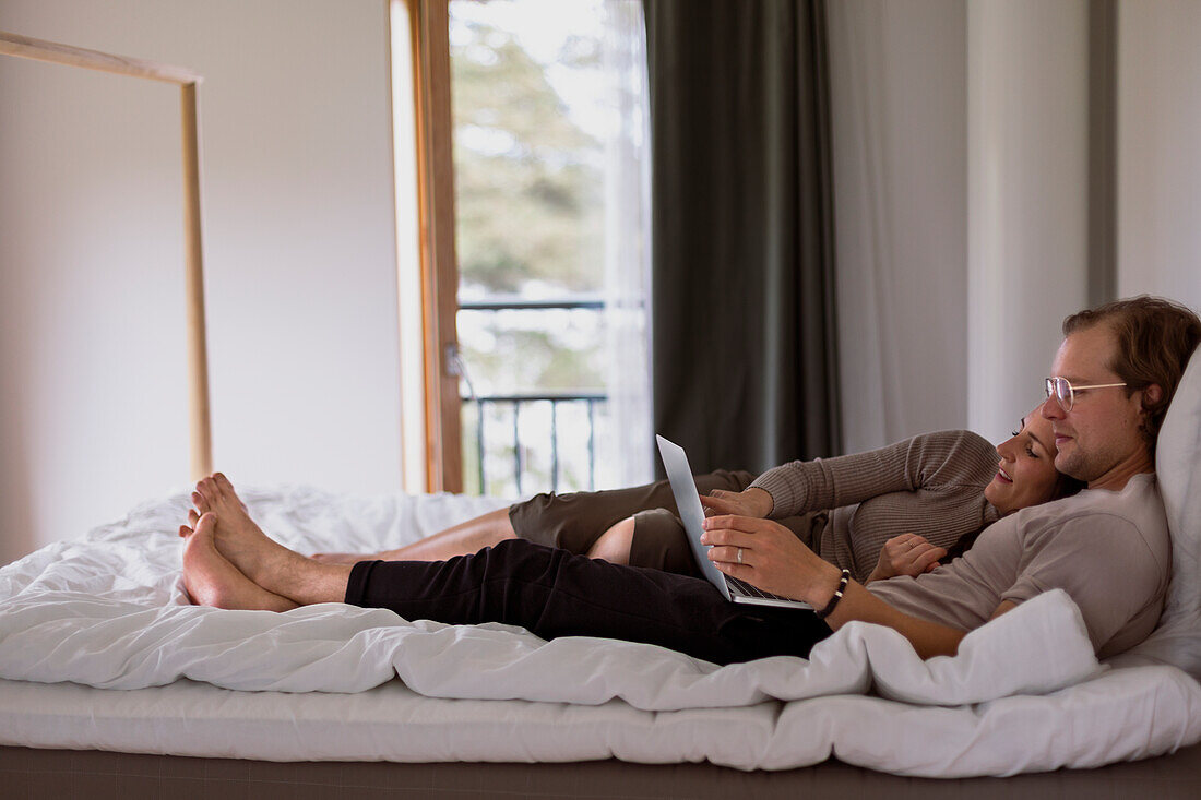 Couple on bed looking at laptop