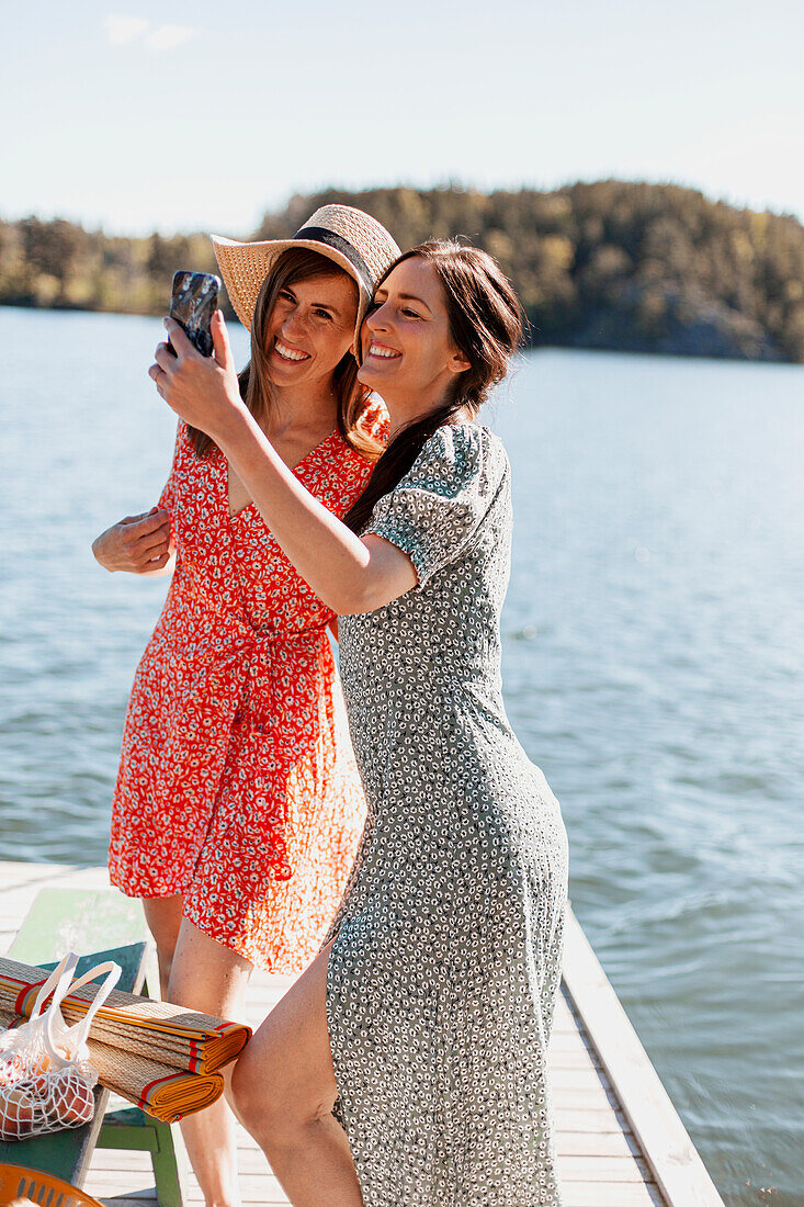 Happy female friends taking selfie on jetty