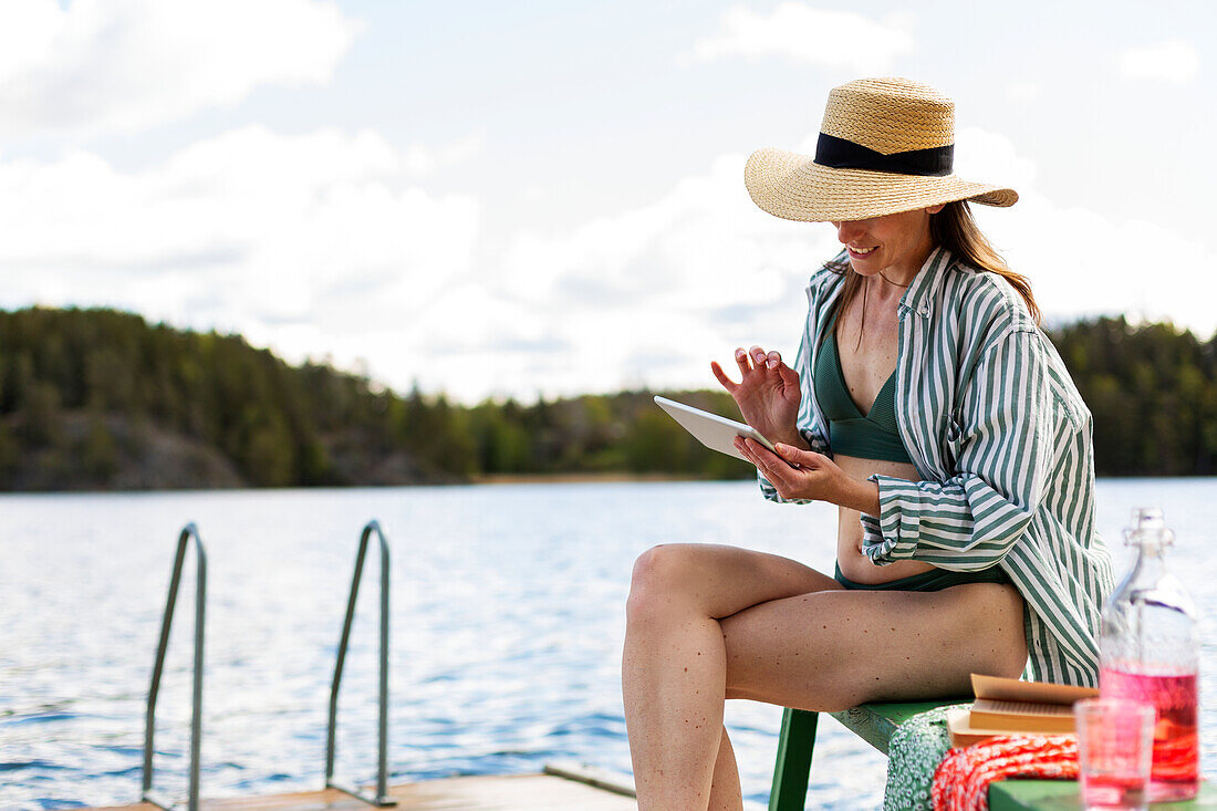 Frau auf Bootssteg schaut auf digitales Tablet