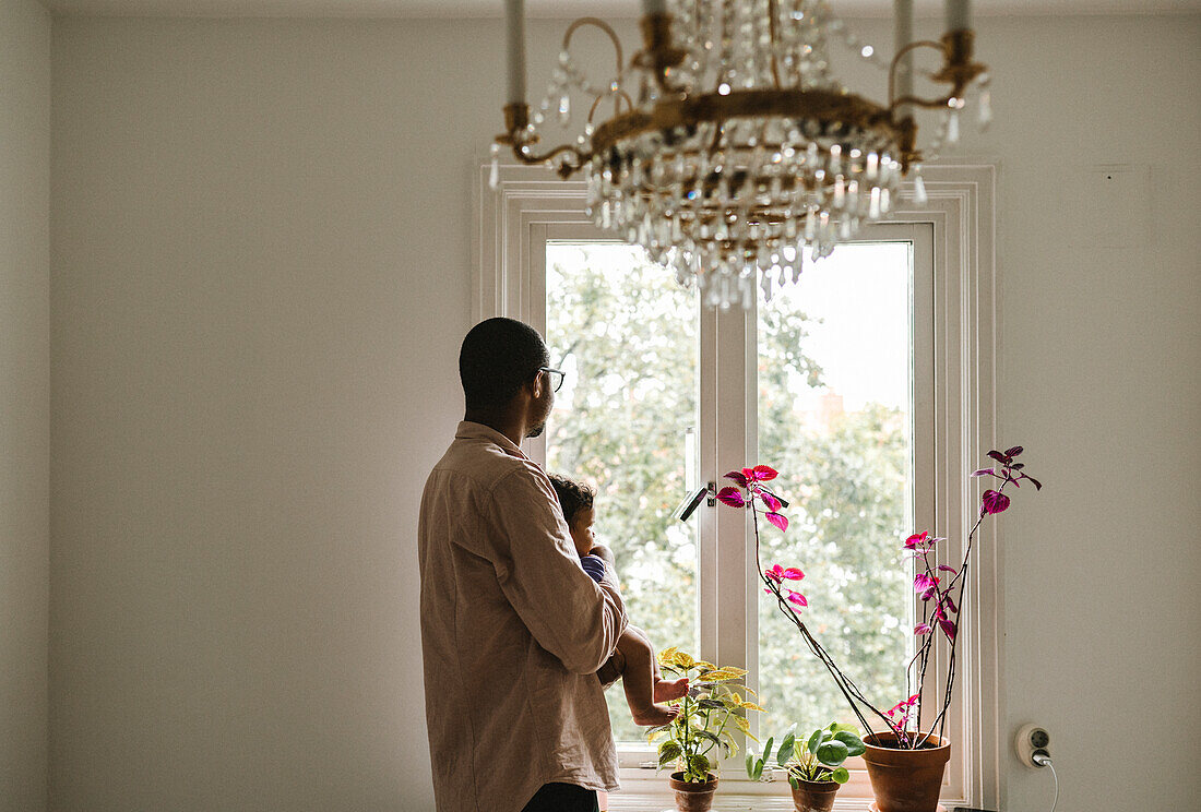 Father with baby looking through window