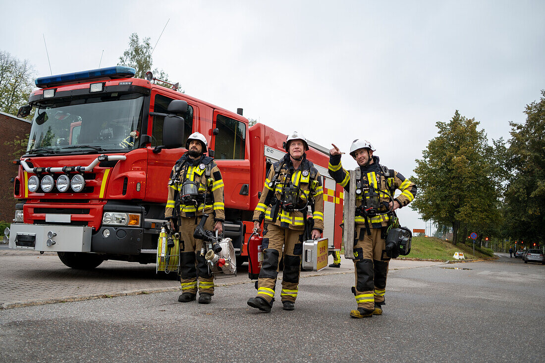 Firefighters walking, fire engine in background