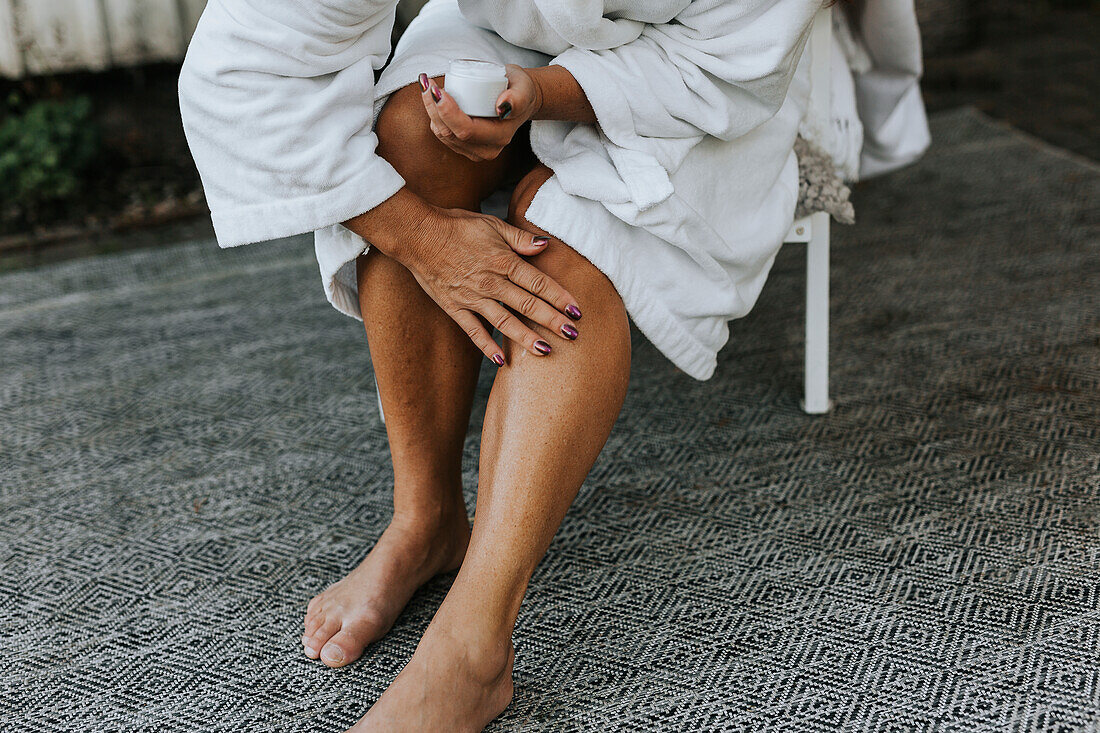Frau trägt Feuchtigkeitscreme auf ihr Bein auf