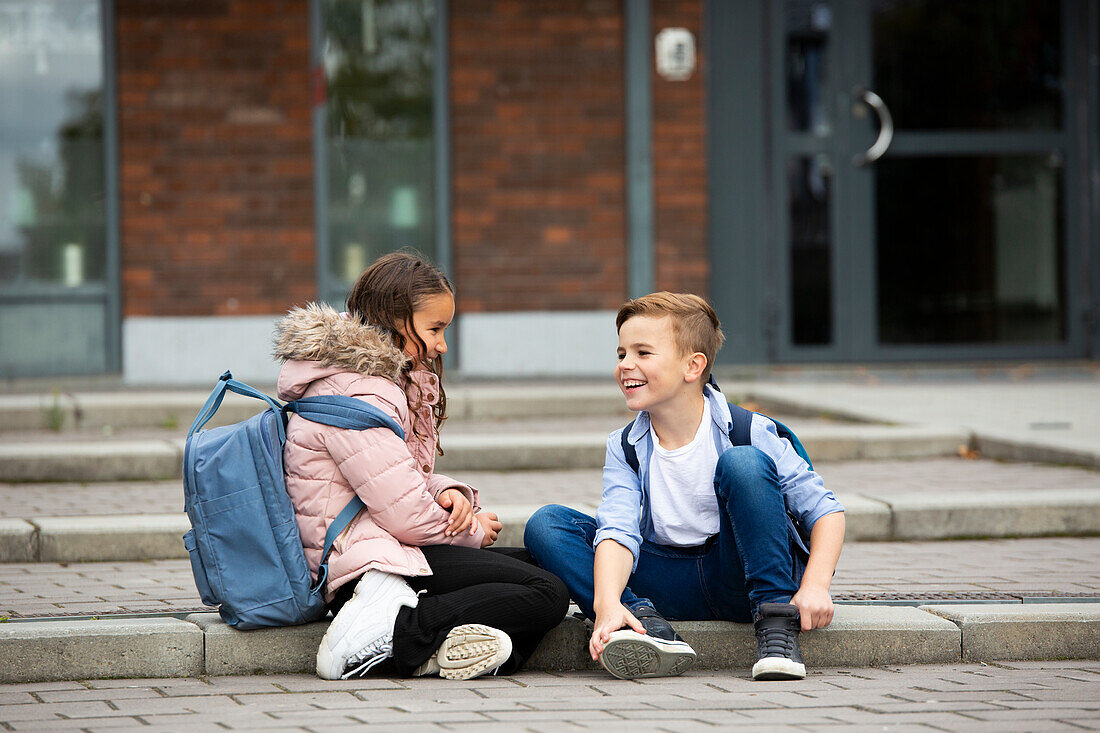 Boy and girl talking in front of school