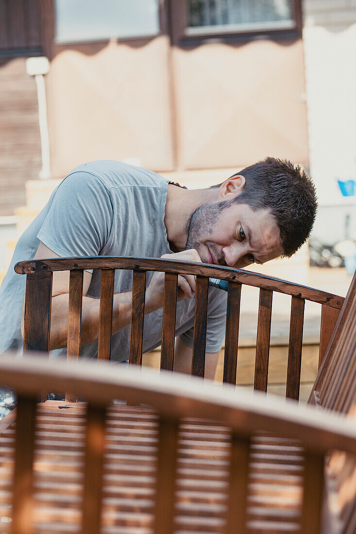 Man painting bench in garden