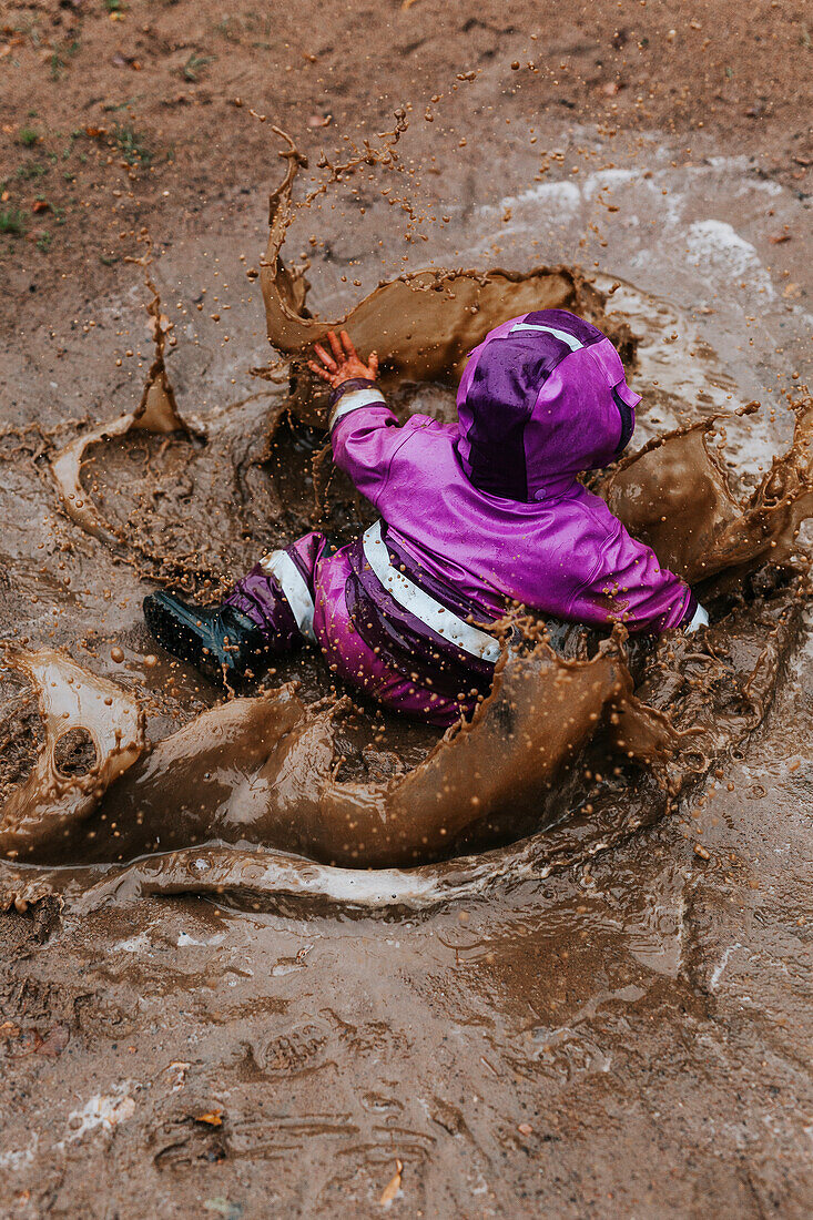 Toddler girl splashing in puddle