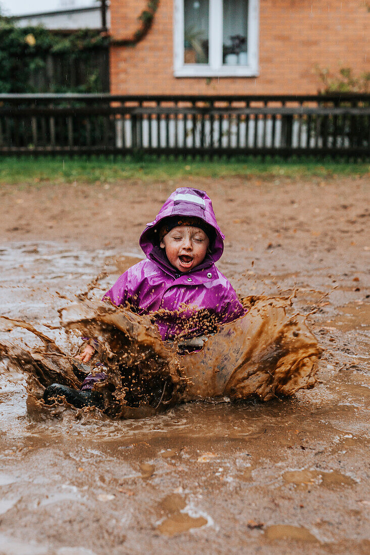 Toddler girl splashing in puddle