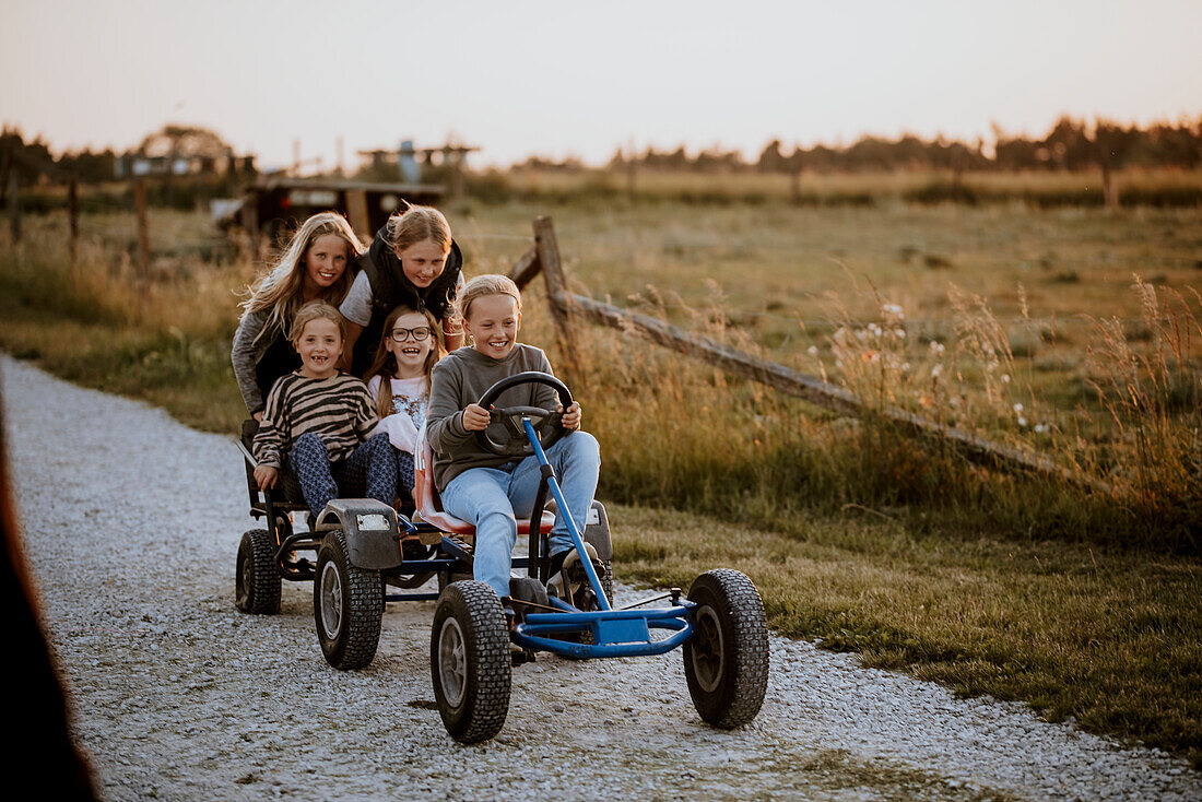 Happy girls riding go-kart on dirt road